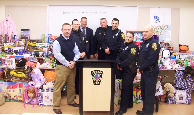 Marion's chief of police, detectives and officers stand in front of the toys collected for kids in foster care on Wednesday. BY MATTHEW BERNAT